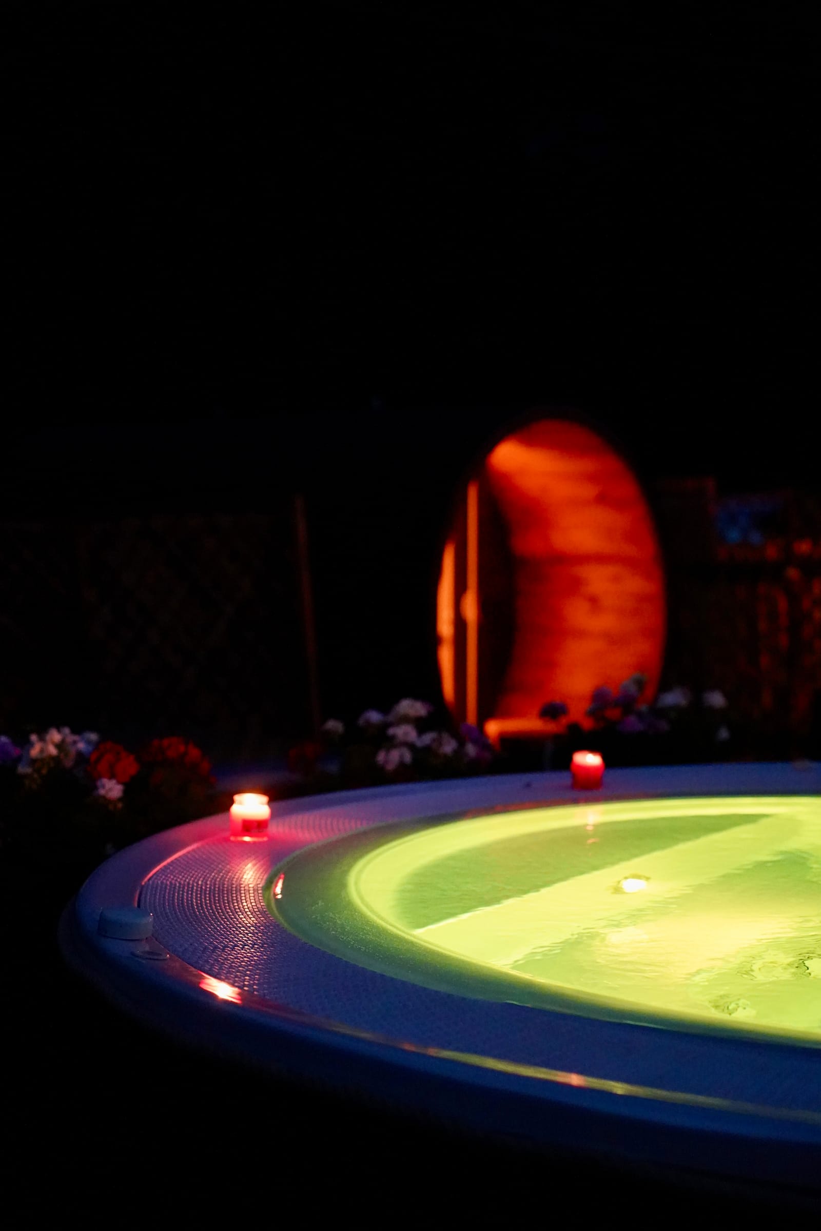 Vasca idromassaggio illuminata di notte con sauna a botte